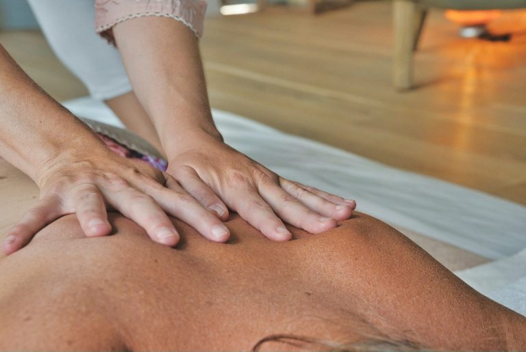 Manuelle Therapie München & Stanzach Eine Person erhält eine Rückenmassage mit beiden Händen auf der Haut.